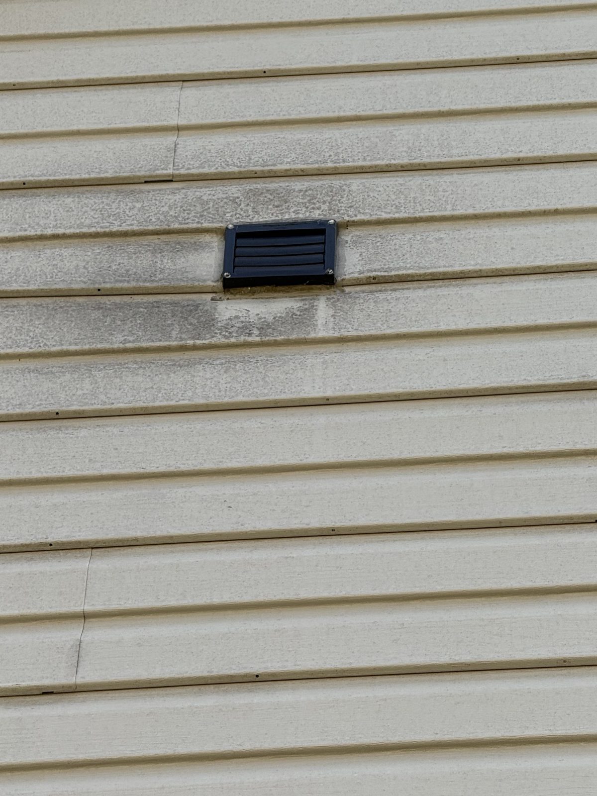 Before - Heavy mold and mildew staining around exterior vent on siding